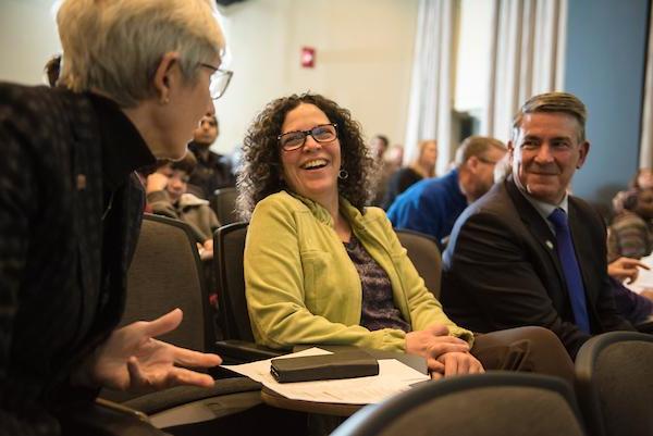A shot of three people laughing at a thesis competition